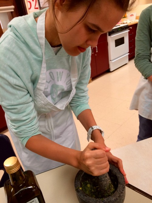 Making pesto with a mortar and pestle.