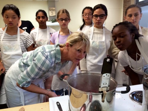 Kim Rizk, owner of Jammin' Crepes, and students in PPS Cooks take note of the temperature creeping up past syrup to jam.