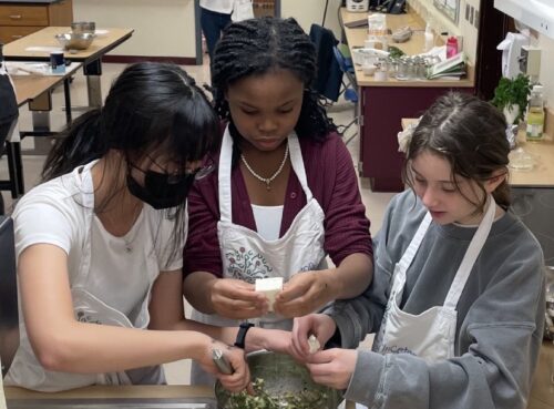 Students adding feta cheese to fritters batter