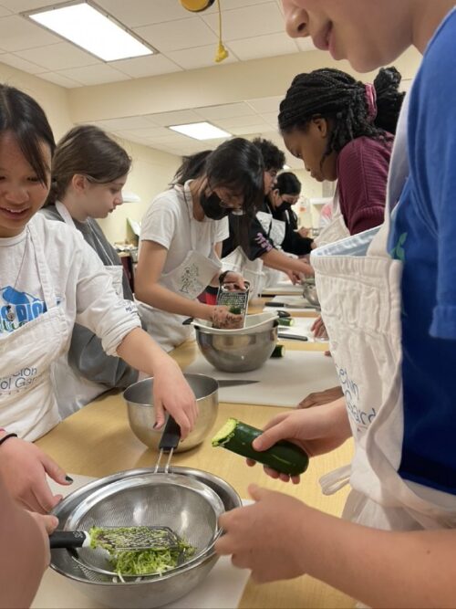 Students grating zucchini in the kitchen